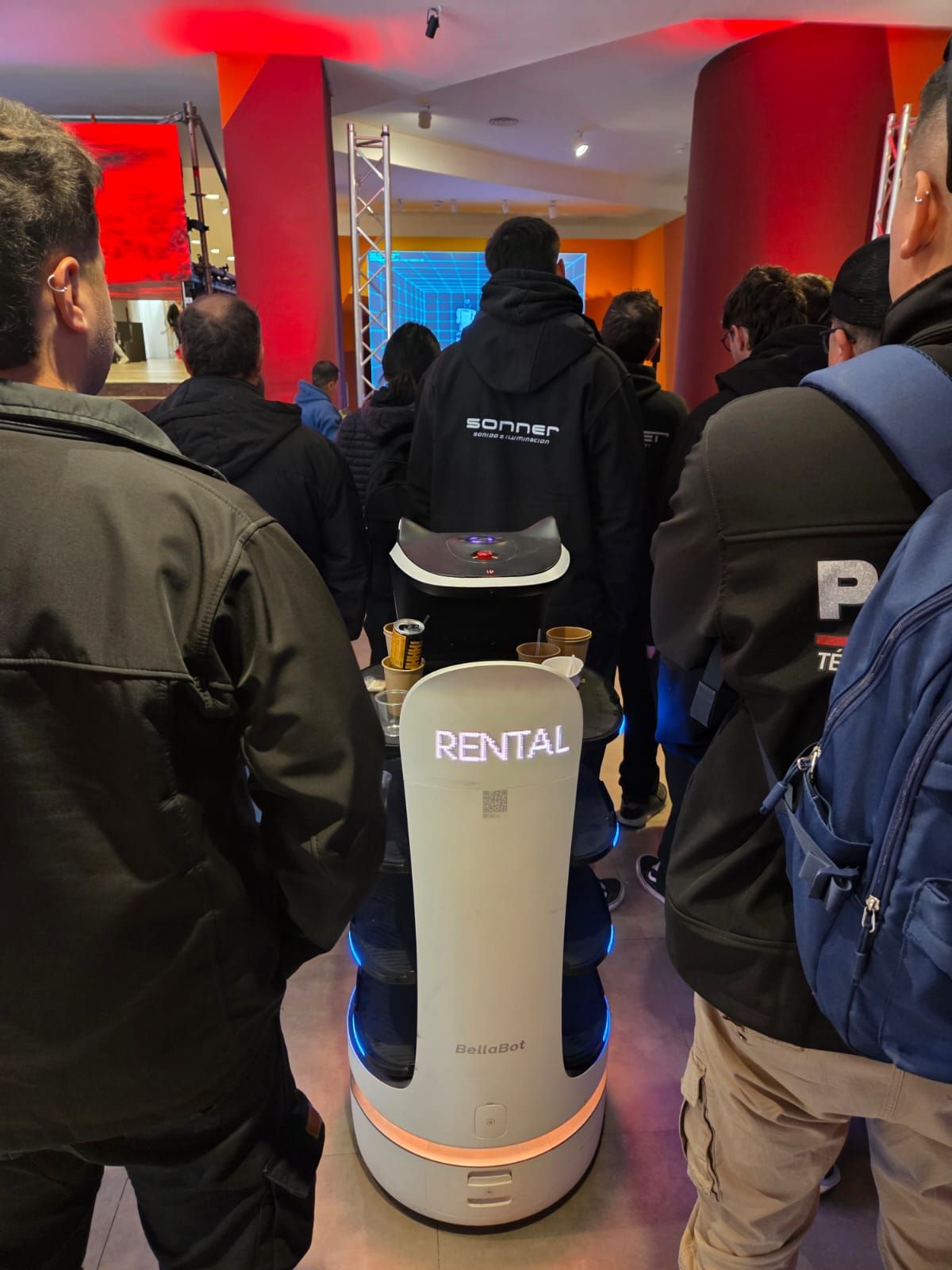 Detalle del robot de servicio con branding Rental Summit entre los asistentes